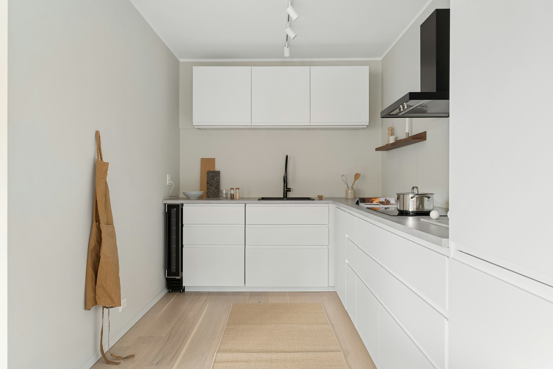 A kitchen with white cabinets and a wooden floor